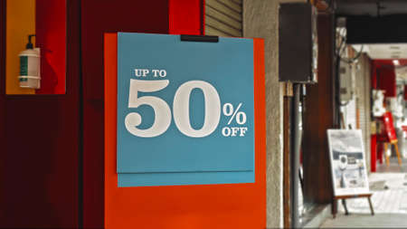 Red sign hanging on a glass window with the inscription up to 50% offの写真素材