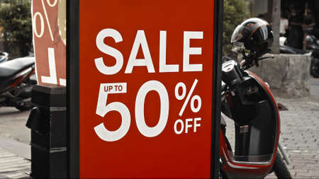 Red sign hanging on a glass window with the inscription sale up to 50% offの写真素材
