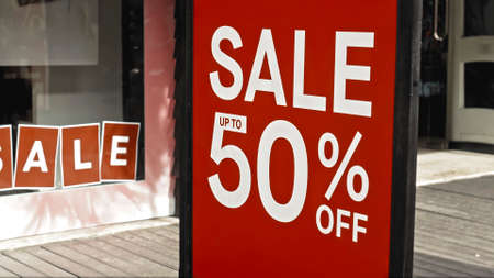 Red sign hanging on a glass window with the inscription sale up to 50% offの写真素材