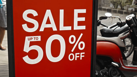 Red sign hanging on a glass window with the inscription sale up to 50% offの写真素材