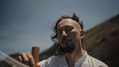 A young Asian guy playing Tibedt singing copper cups on a viewing mountain in nature