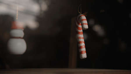 Small white and red Christmas decorations candy cane hanging on a thread behind the glass in the...