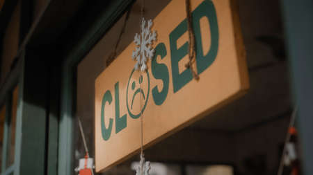 A sign hanging on the door of the institution with a glass window with the inscription closed with...