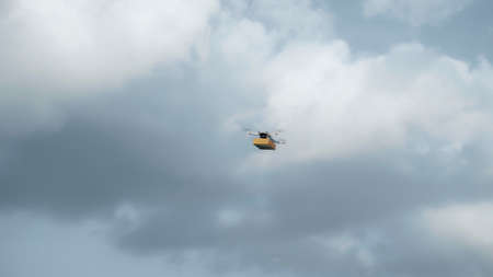Photo of a flying on a sky delivery drone with holding a cardboard parcelの写真素材