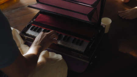 man seated on a wooden floor and playing a keyboard ethnic Indian instrument harmoniumの写真素材