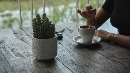 A young European girl sits at a table in a public place with a cup of coffee on a wooden tableの写真素材