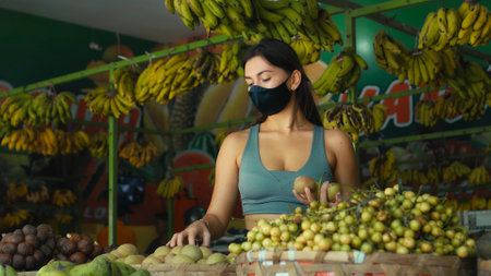 A young European girl in a black protective mask buys organic fruits in a store