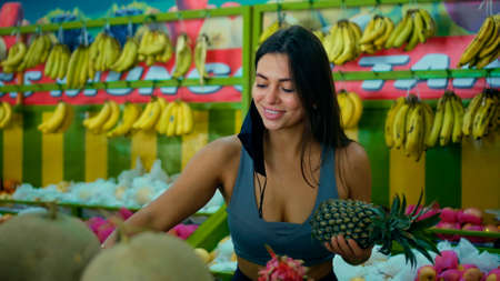 A young European girl in a black protective mask buys organic fruits in a storeの写真素材