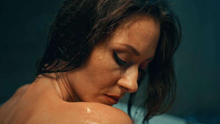 Young European girl long-haired brunette lies in the bathroom with red flowers on spa procedure