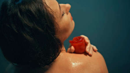 Young European girl long-haired brunette lies in the bathroom with red flowers on spa procedureの写真素材