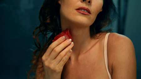 Young European girl long-haired brunette sits in the bathroom with red flowers on a spa procedure with soap in the shape of a roseの写真素材