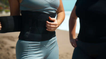 Young European sports girl stands on the beach in the belt for weight loss with sweat withdrawal for fitness occupationの写真素材