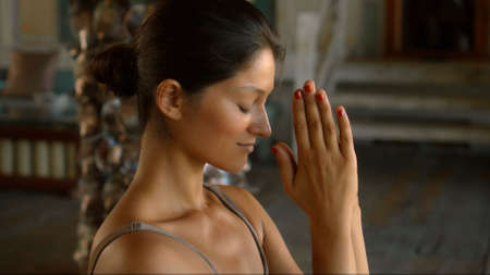 A young European brunette girl sits on a towel and is engaged in yoga in the lounge roomの写真素材