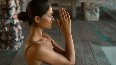 A young European brunette girl sits on a towel and is engaged in yoga in the lounge roomの写真素材