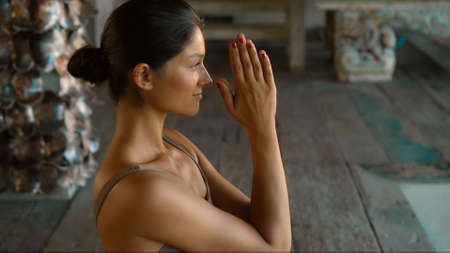 A young European brunette girl sits on a towel and is engaged in yoga in the lounge roomの写真素材