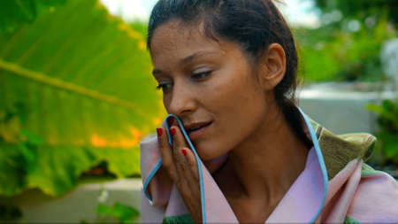 Young European brunette girl wipes a towel in the backyard with a green garden on the backgroundの写真素材