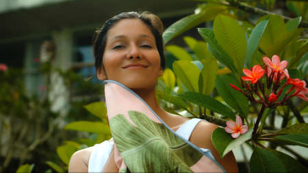 Young European brunette girl wipes a towel in the backyard with a green garden on the backgroundの写真素材
