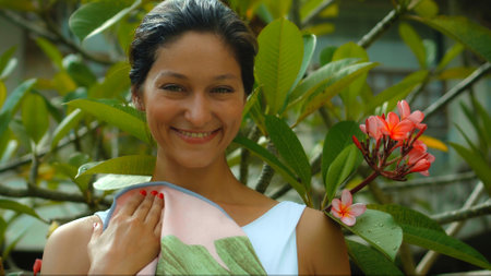 Young European brunette girl wipes a towel in the backyard with a green garden on the backgroundの写真素材