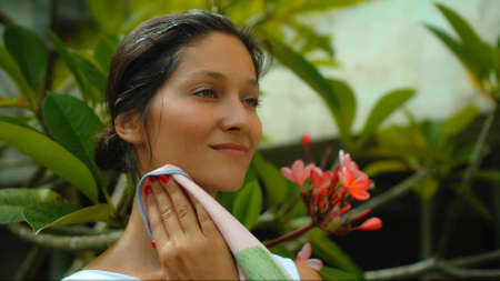 Young European brunette girl wipes a towel in the backyard with a green garden on the backgroundの写真素材