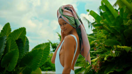 Young European brunette girl with a towel on her head in the backyard with a green garden on the backgroundの写真素材