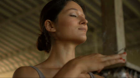 A young European brunette girl sits on a towel and is engaged in yoga in the lounge roomの写真素材