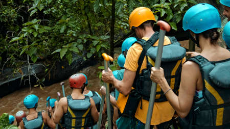 People descending stairs in black protective jackets with yellow lines and protective helmets for rafting and with weightsの写真素材