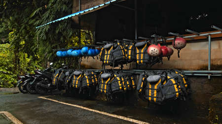 Black protective jackets with yellow lines and protective helmets to practice rafting hanging on a wall on the streetの写真素材