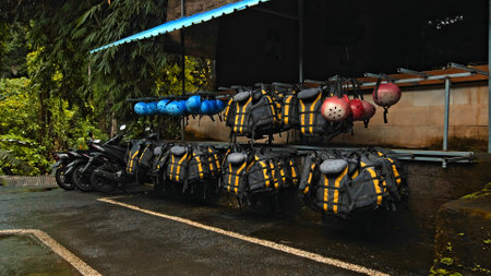 Black protective jackets with yellow lines and protective helmets to practice rafting hanging on a wall on the streetの写真素材