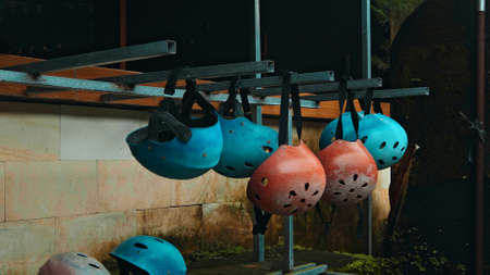 Colored protective helmets for the head to practice rafting hanging on the wall on the streetの写真素材