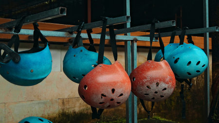 Colored protective helmets for the head to practice rafting hanging on the wall on the streetの写真素材