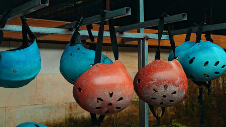 Colored protective helmets for the head to practice rafting hanging on the wall on the streetの写真素材