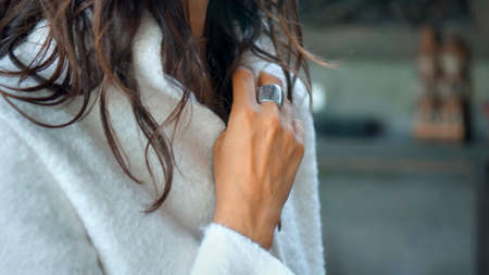 Young and beautiful European girl at home in autumn clothes and a white sweater touches clothes with her handsの写真素材