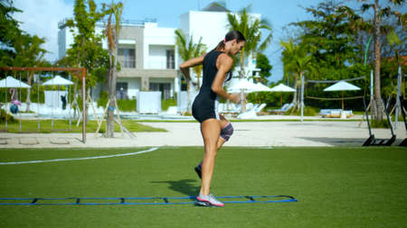 Young sports European brunette girl takes stop steps in the grid along the sports field with a green lawnの写真素材