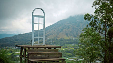 View of a green mountain from the far covered by fog and clouds with a standing door in the middleの写真素材