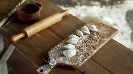 Traditional rustic Russian fresh handmade dumplings lying on the wooden table on the cutting boardの写真素材