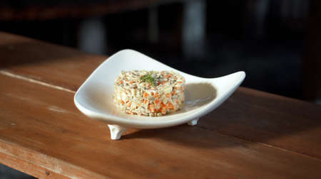Traditional Russian fresh olivier salad lying on a wooden table in a white plateの写真素材