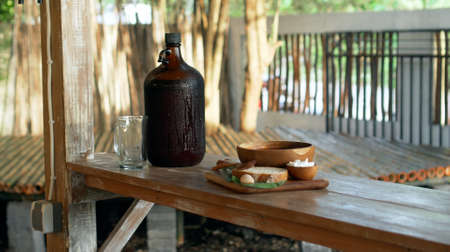 Traditional Russian fresh hot soup borsch with beetroot, red color, with sour cream and fresh bread in a wooden plate standing on a wooden table in the villageの写真素材