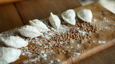 Traditional rustic Russian fresh handmade dumplings lying on the wooden table on the cutting boardの写真素材