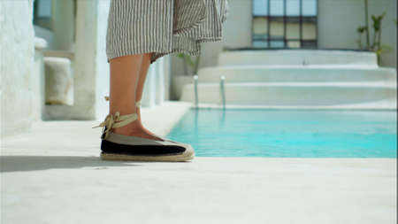 Legs of European girls in dresses going in shoes on a backyard near the poolの写真素材