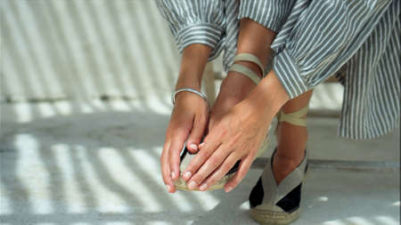 European girl's legs in a dress sitting in shoes on chair on backyardの写真素材