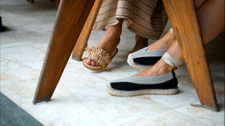 Legs of European ladies sitting in long dresses in the backyard by the table