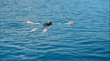 The young guy floats on the surface of the water
