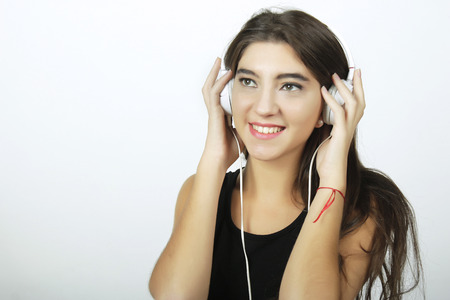 Trendy and stylish young girl listening to music with white headphones.