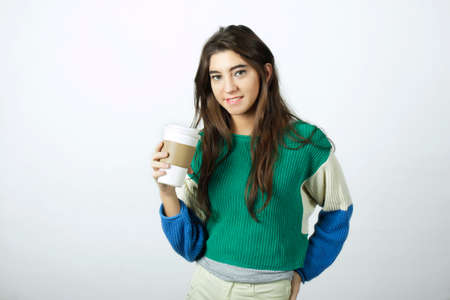 Attractive young woman drinking coffee out of a disposable cup.の写真素材