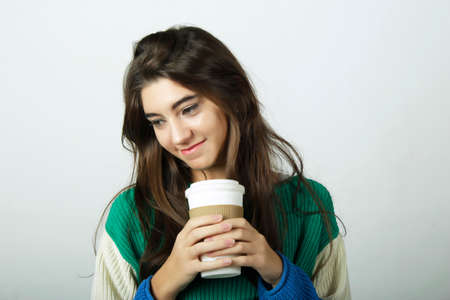 Attractive young woman drinking coffee out of a disposable cup.の写真素材