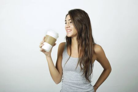 Attractive young woman drinking coffee out of a disposable cup.