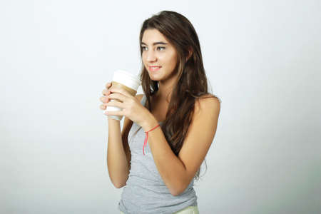 Attractive young woman drinking coffee out of a disposable cup.の写真素材