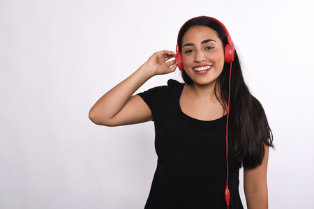 Young beautiful woman listening to music indoor. Isolated white background.の写真素材