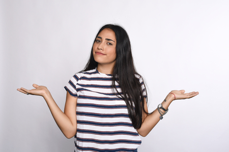 Indecisive young woman with arms open. Isolated white background.の写真素材