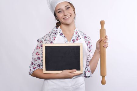 young woman chef with empty menu blackboard and rolling pin. Isolated on white background.の写真素材